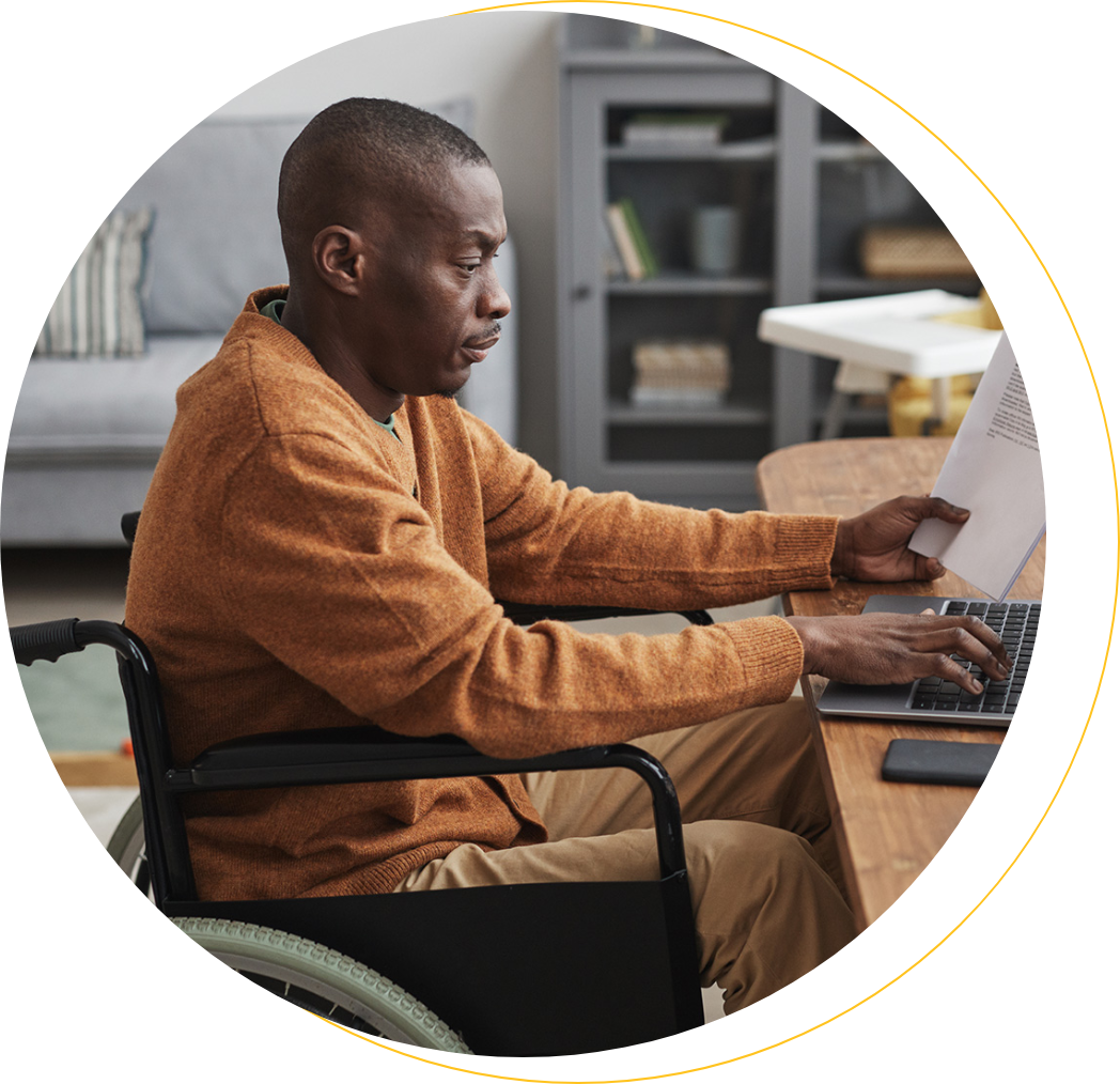 African-American man using wheelchair working from home in minimal grey interior